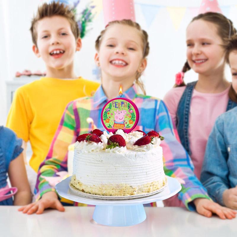 Vela de Peppa Pig colocada en una torta de cumpleaños con niños celebrando.